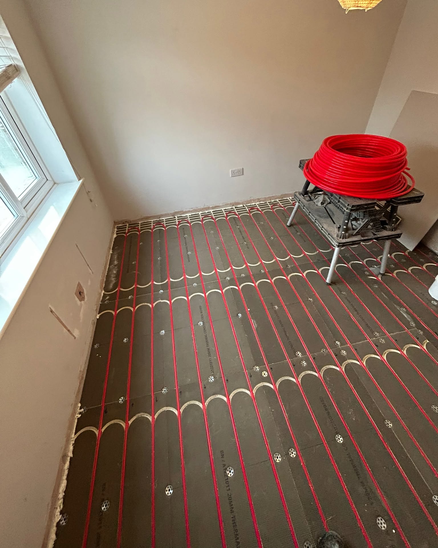 Underfloor heating install progressing across a domestic bedroom, Greater Manchester