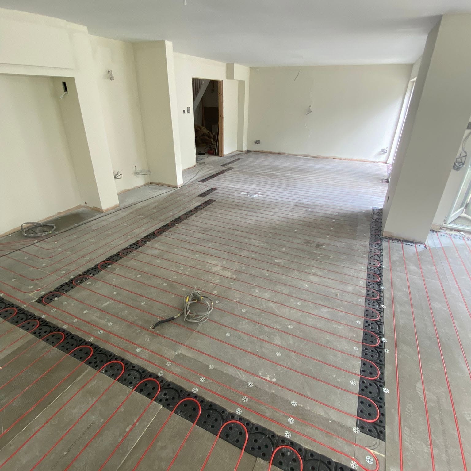 Wet underfloor heating pipe loops laid on staple boards in a Greater Manchester kitchen